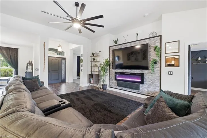 Spacious living area featuring wood-finish flooring and a contemporary ceiling fan