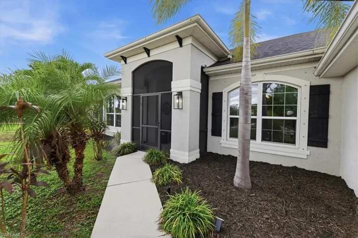 Contemporary stucco exterior with a screened entry, decorative shutters, arched windows, and established landscaping