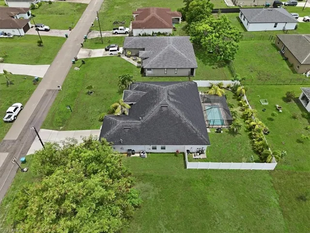 Residential property featuring a screened-in swimming pool, a white privacy fence, and a large grassy yard