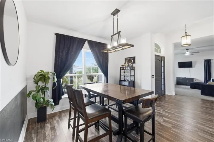 Dining area featuring wood-finish flooring, a contemporary chandelier, and a large window