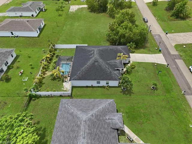 White single-story residence featuring a dark shingle roof, a screened-in swimming pool, and a concrete driveway