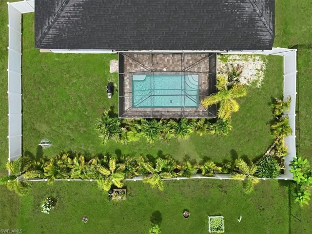 Expansive green lawn with a screened-in swimming pool and surrounding paved patio