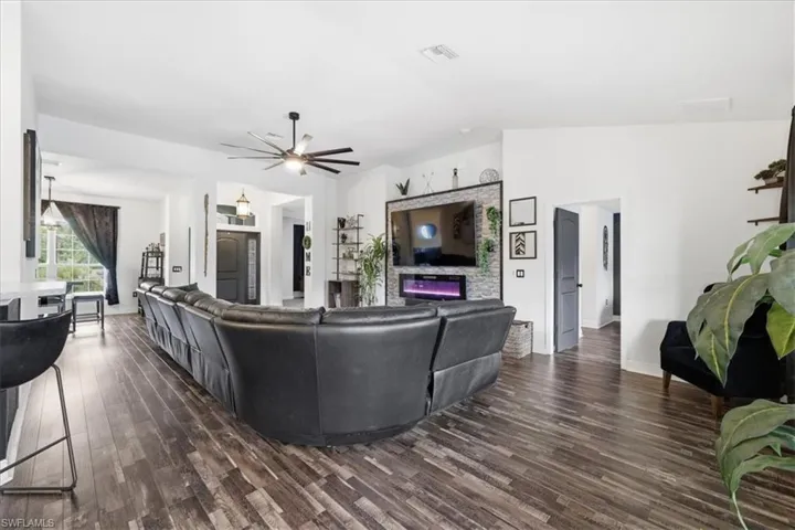 Spacious living area featuring wood-finish flooring, a contemporary ceiling fan, and an accent wall with stacked stone detailing