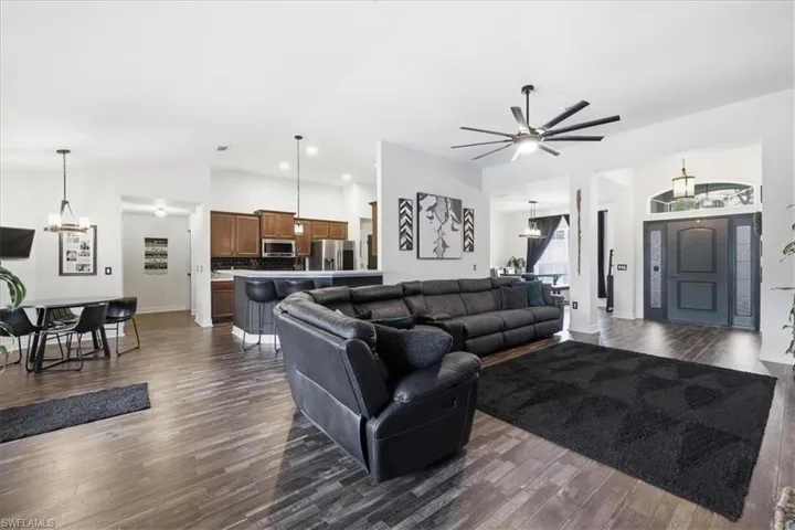 Open-concept living area featuring wood-finish flooring, a contemporary ceiling fan, and high ceilings