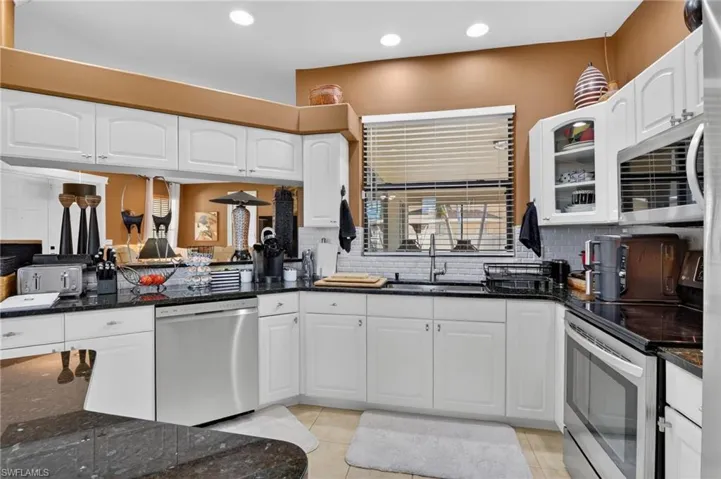 Updated kitchen with granite counters, white cabinets, plant shelves