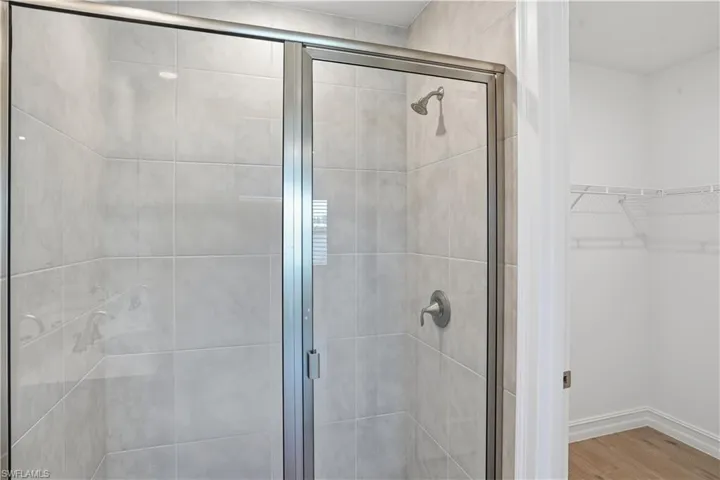 Bathroom featuring a stall shower, a walk in closet, and light wood-type flooring