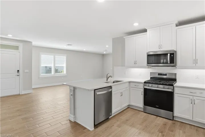 Kitchen featuring stainless steel appliances, light wood-style floors, white cabinetry, tasteful backsplash, and recessed lighting