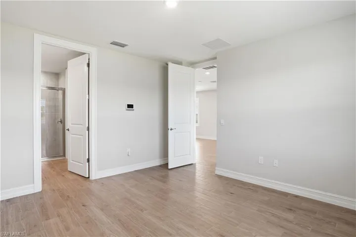Unfurnished bedroom with light wood-style floors and connected bathroom