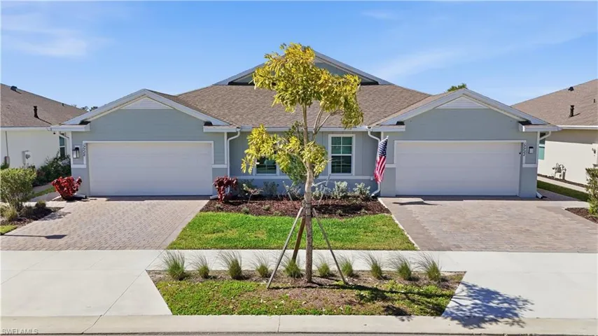 Ranch-style house with a garage, driveway, and a shingled roof