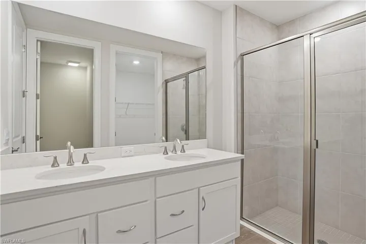 Bathroom with a shower stall, double vanity, and a spacious closet