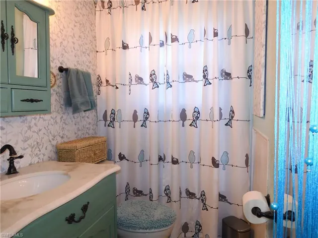 Bathroom with vanity with extensive cabinet space and toilet