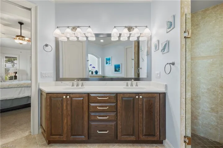 Full bathroom with a sink, double vanity, ensuite bath, and a shower stall