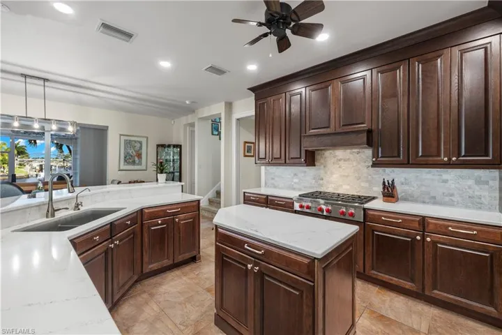 Kitchen with tasteful backsplash, visible vents, stainless steel gas stovetop, hanging light fixtures, and a sink