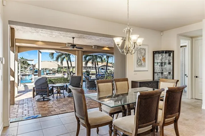 Dining space with ceiling fan with notable chandelier and light tile patterned floors