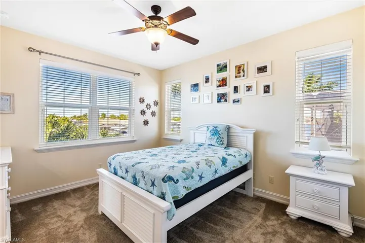 Bedroom featuring baseboards, dark carpet, and a ceiling fan
