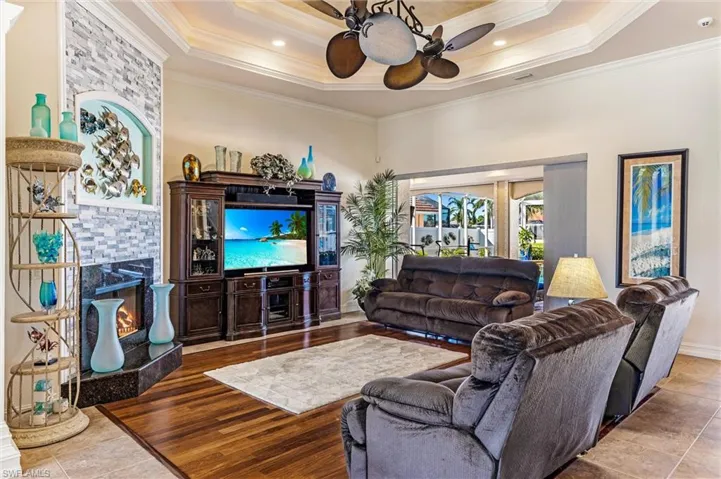 Living area with wood finished floors, ornamental molding, a fireplace, and a raised ceiling