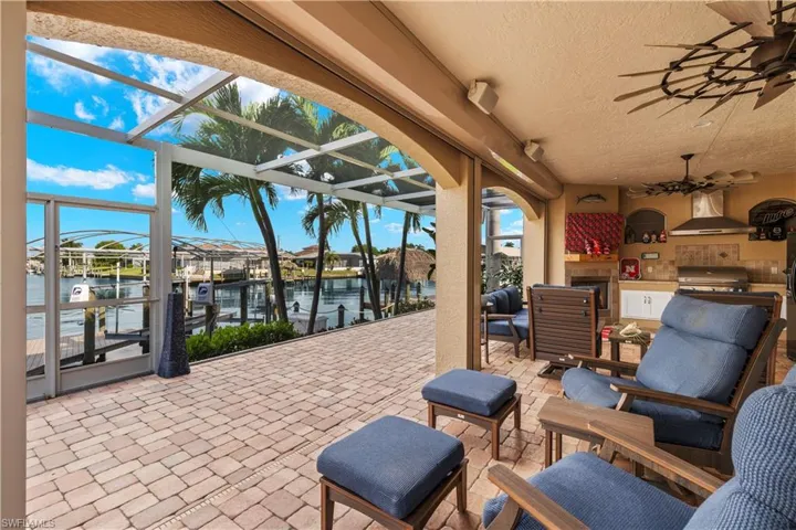 View of patio featuring area for grilling, a boat dock, boat lift, a water view, and a lanai