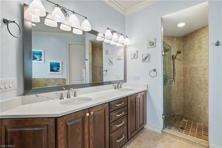Full bathroom with crown molding, a stall shower, tile patterned flooring, and a sink