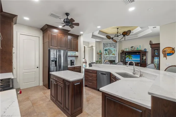 Kitchen with visible vents, a spacious island, ornamental molding, a tray ceiling, and a sink