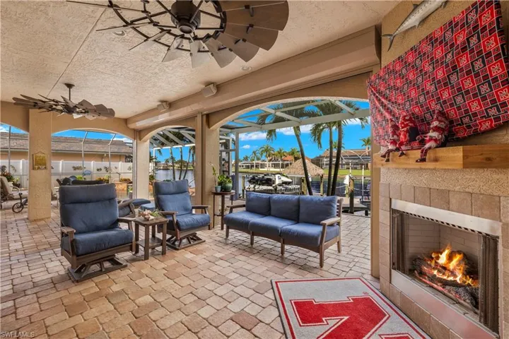 View of patio featuring a lanai, a lit fireplace, and a ceiling fan