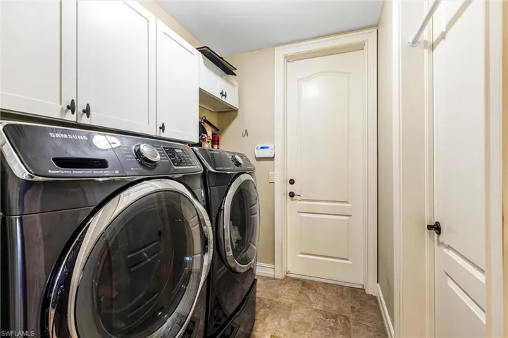Laundry area featuring cabinet space, baseboards, and washer and clothes dryer
