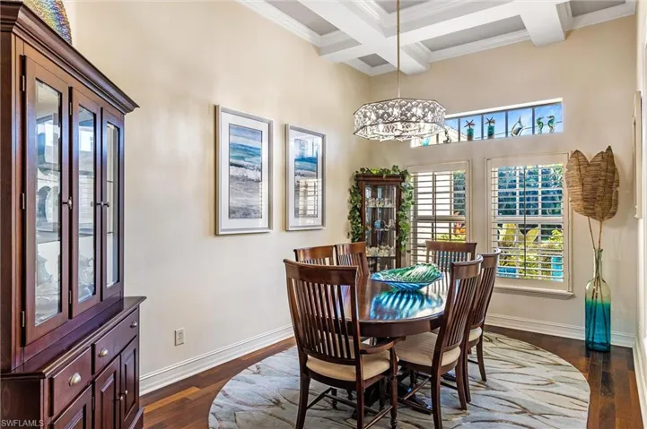 Dining room featuring baseboards, coffered ceiling, dark wood-style floors, ornamental molding, and beamed ceiling