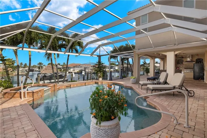 View of pool featuring a boat dock, a patio area, glass enclosure, and an outdoor kitchen