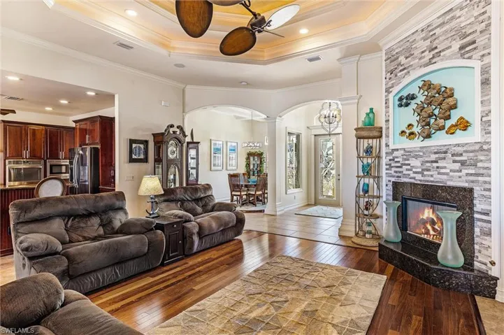 Living room featuring ornamental molding, wood-type flooring, visible vents, and ornate columns