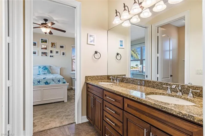 Ensuite bathroom with double vanity, ensuite bath, a sink, and ceiling fan with notable chandelier