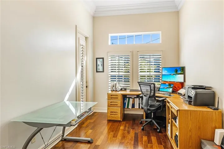 Office space featuring dark wood-style floors, crown molding, and baseboards