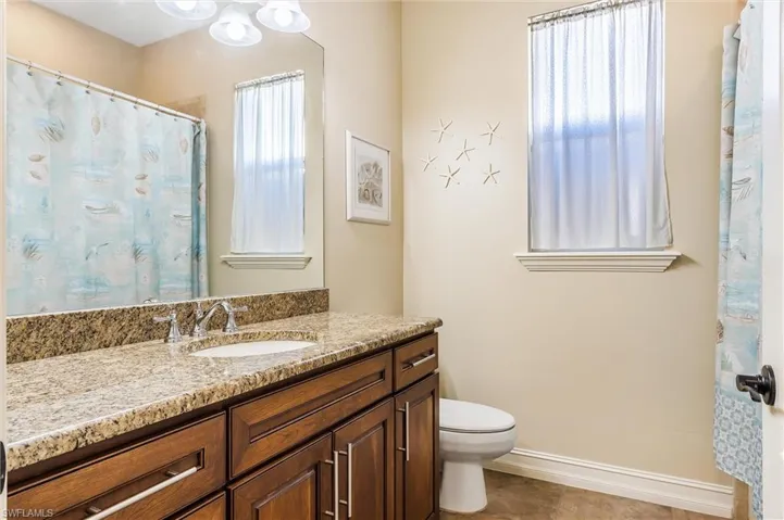 Full bathroom with tile patterned floors, vanity, toilet, and baseboards