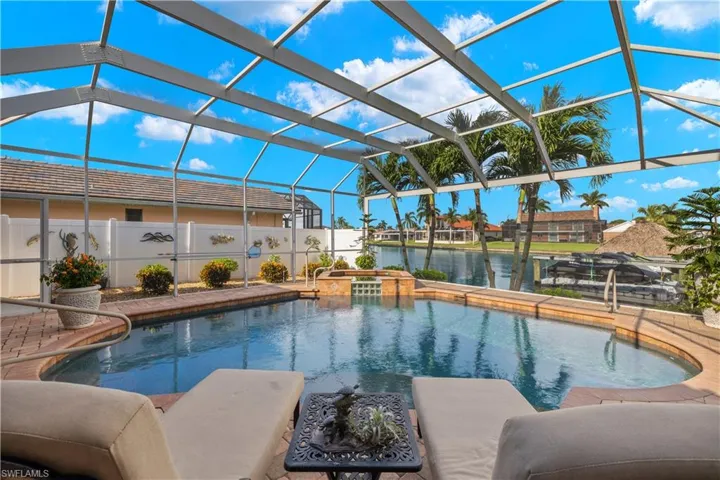 View of swimming pool with a lanai, a water view, a pool with connected hot tub, and a patio