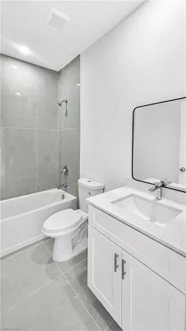 Full bath featuring vanity, shower / washtub combination, and light tile patterned flooring