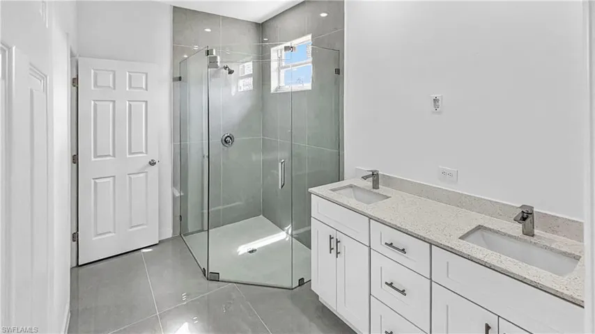 Full bathroom featuring double vanity, a shower stall, and light tile patterned floors