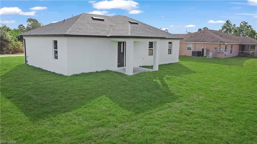 Back of house with stucco siding, a yard, and a patio area