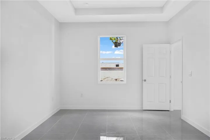 Empty room with a tray ceiling and dark tile patterned floors