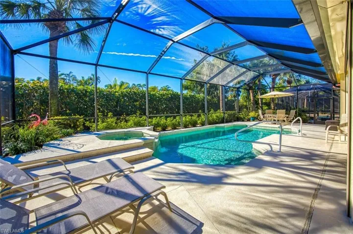 View of swimming pool featuring a sunroom, a patio, glass enclosure, and a pool with connected hot tub