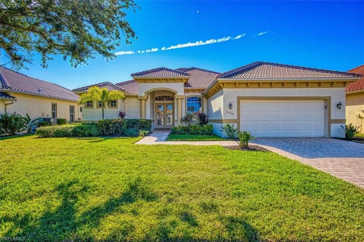 Mediterranean / spanish home featuring a front lawn, stucco siding, decorative driveway, a tile roof, and an attached garage