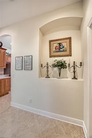 Corridor with a textured wall, arched walkways, and light tile patterned floors