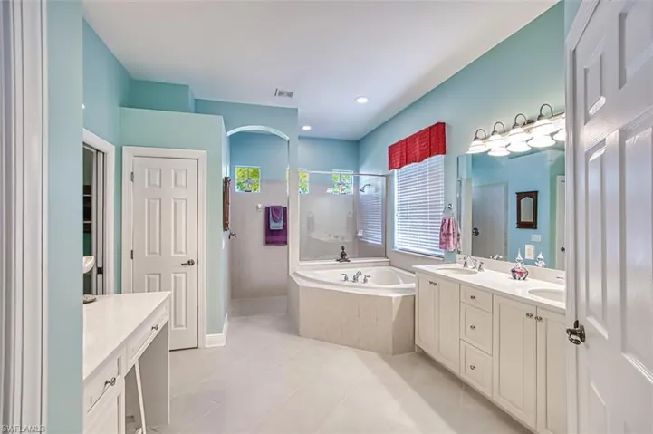 Bathroom featuring double vanity, a garden tub, a walk in shower, light tile patterned flooring, and recessed lighting