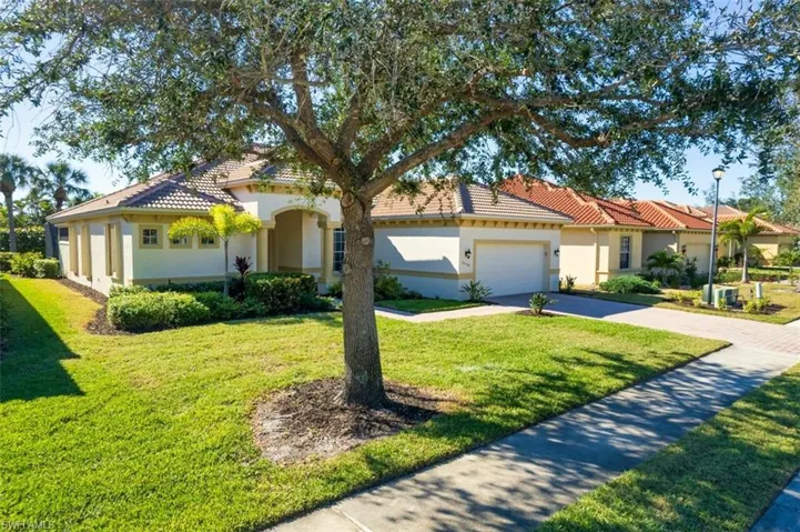 Mediterranean / spanish-style home with driveway, stucco siding, a front yard, and a tile roof