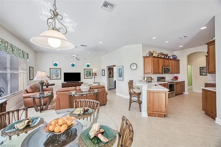 Dining area featuring arched walkways, light tile patterned floors, a ceiling fan, and recessed lighting