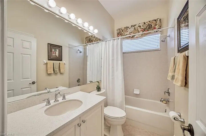 Bathroom with vanity, shower / bathtub combination with curtain, and light tile patterned floors