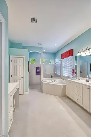 Bathroom with vanity, walk in shower, a garden tub, and light tile patterned floors