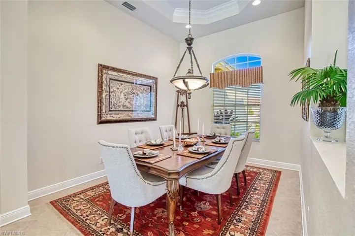 Dining room featuring ornamental molding, a raised ceiling, and light tile patterned floors