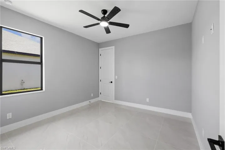 Tiled empty room featuring a wealth of natural light and ceiling fan