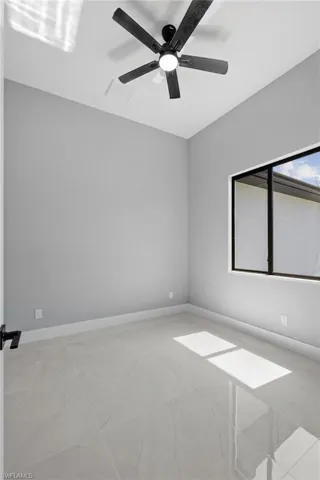 Tiled empty room featuring ceiling fan