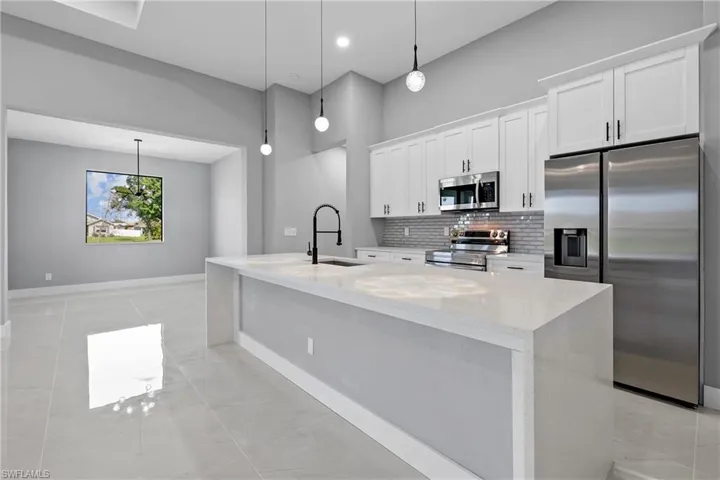 Kitchen with light tile patterned flooring, sink, light stone countertops, appliances with stainless steel finishes, and backsplash