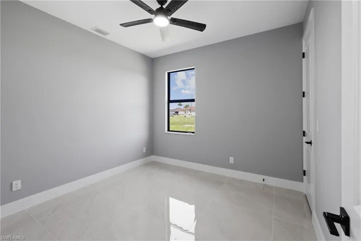 Tiled spare room featuring ceiling fan