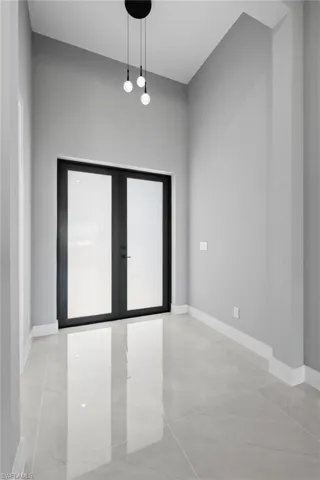 Empty room with french doors and light tile patterned floors